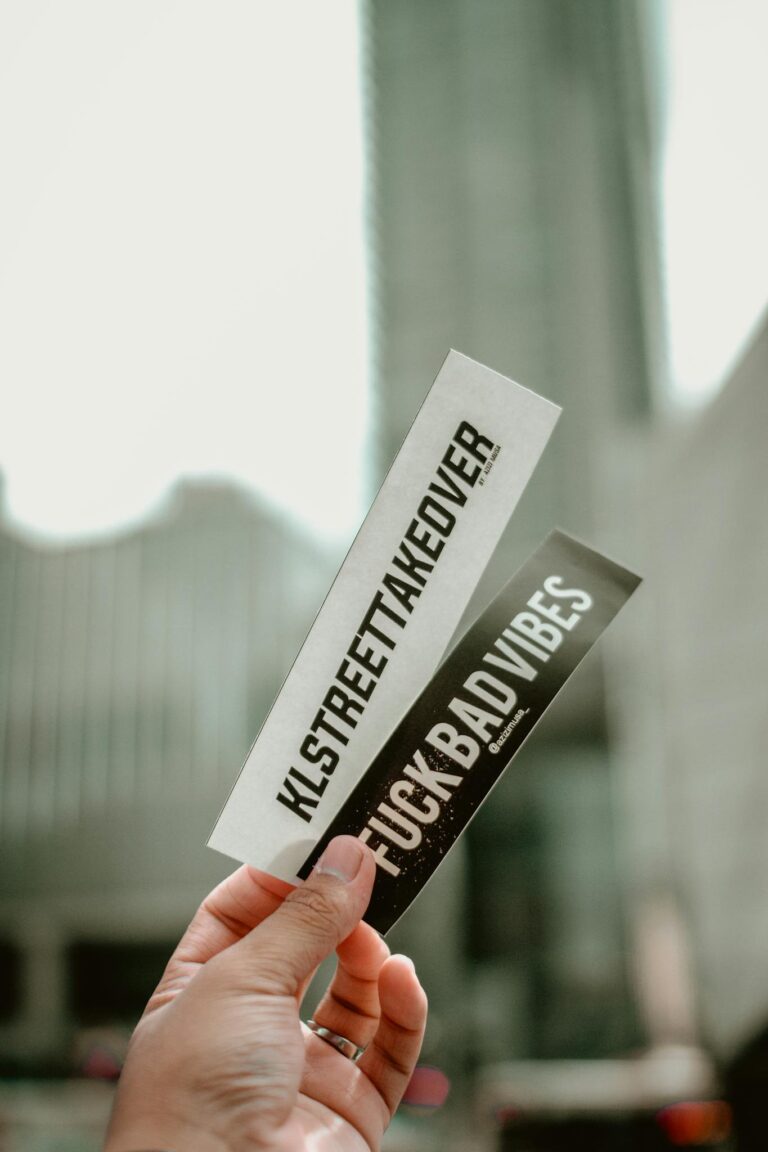 Close-up of hand holding motivational stickers against a city backdrop.
